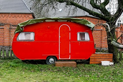 Der knallrote Wohnwagen im Garten der Villa-Heimat steht für jeder Zeit für Spiel und Spaß bereit