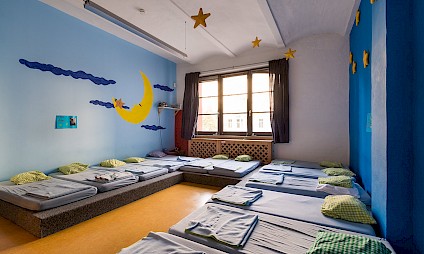 A bedroom in smoothing blue tones with moon and stars on the wall